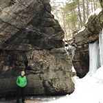 man in front of steep rocks and ice