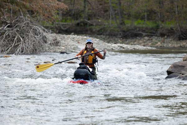 person in kayak paddling down river