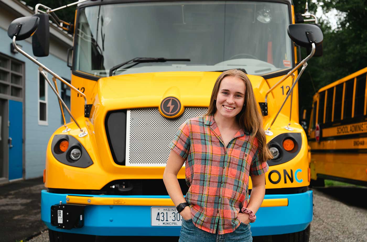 Brynne standing in front of electric school bus