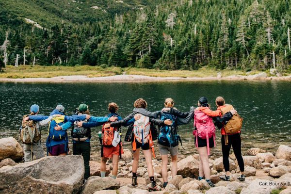 people with arms around each other, backs to camera, facing Katahdin