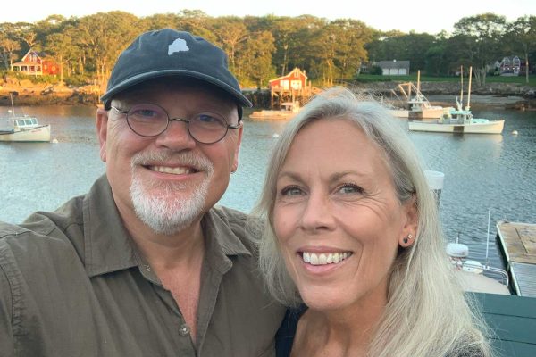 Todd and Laura smiling in front of coastal community