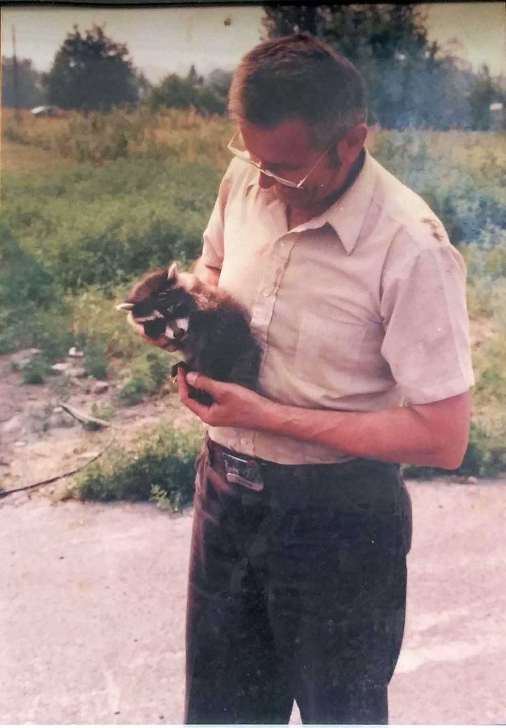 Man holding baby raccoon