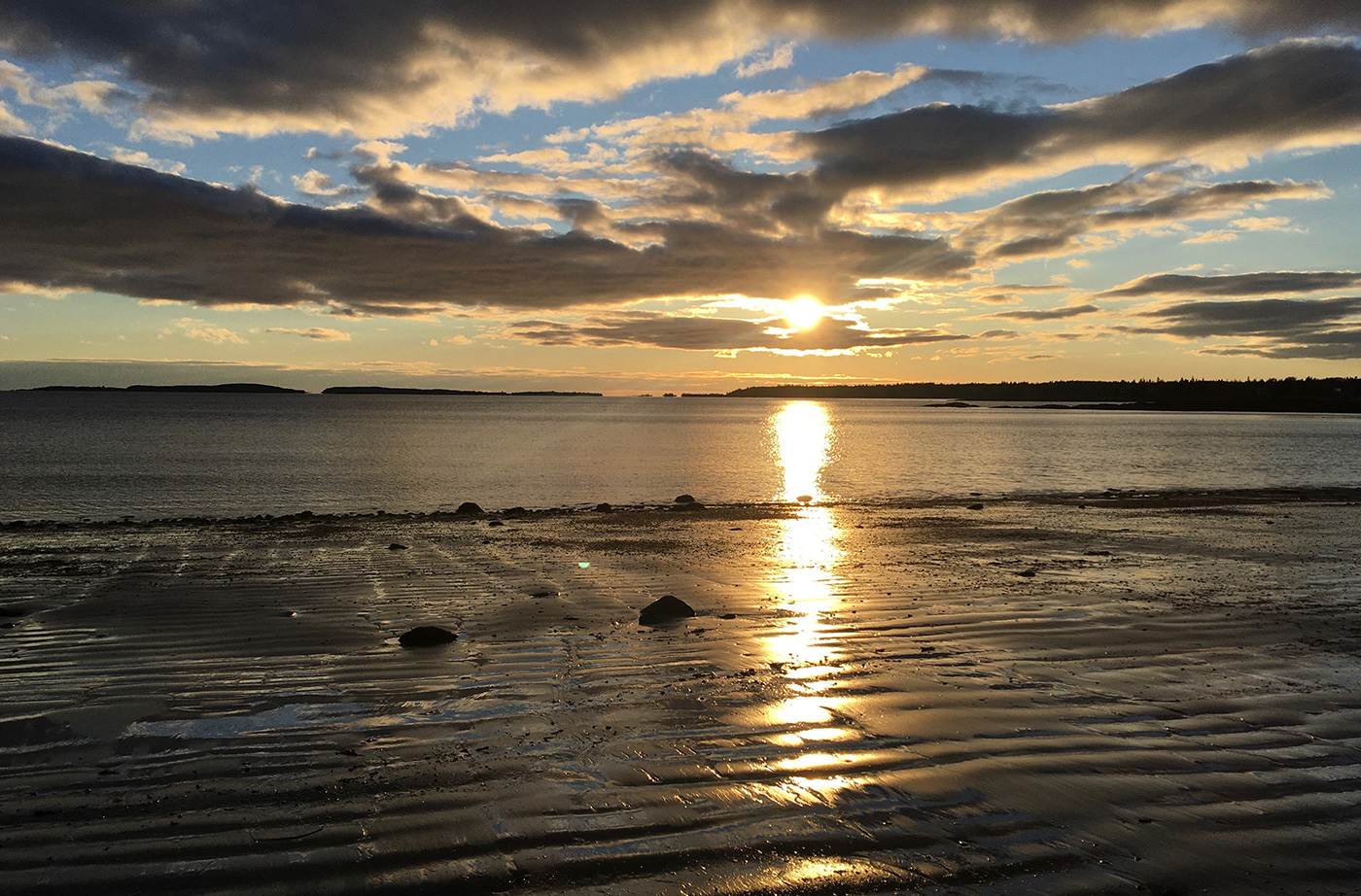 sunset over calm ocean and rippling water on beach sand