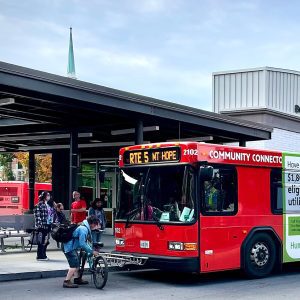 person putting bike on front of public transit bus