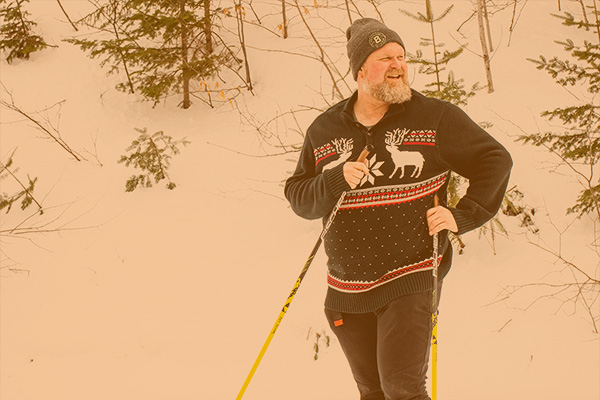 Gabe Perkins wearing ski hat, sweaters, on skis in snow