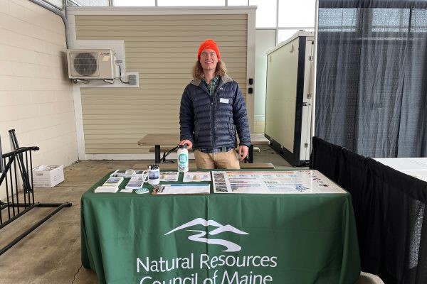 Josh smiling and standing behind NRCM table of materials